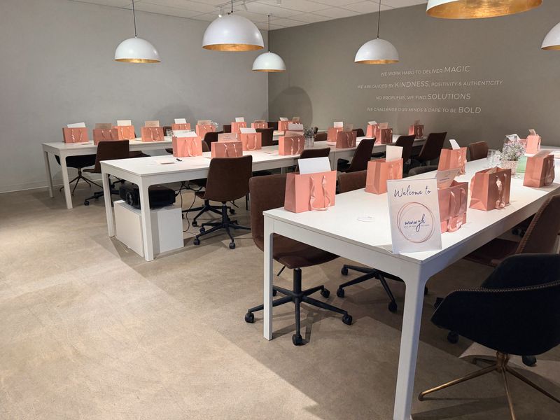 The room set for What We Wish You Knew, with a welcome sign and pink gift bags down the tables